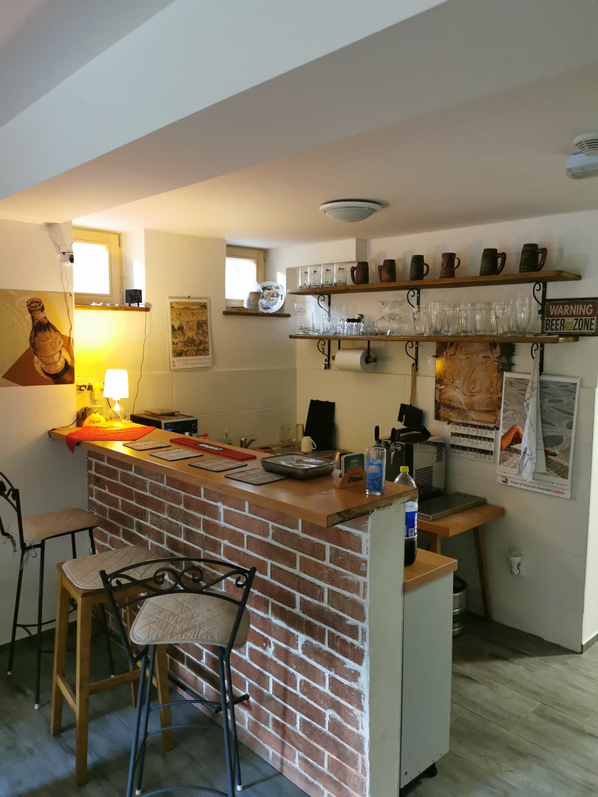 Cihlový bar s pípou a policemi s korbely