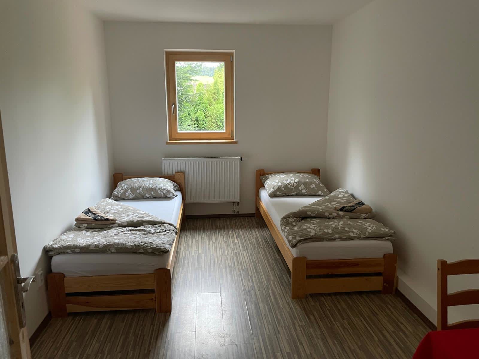 Dvoulůžkový pokoj s dřevěnými postelemi a oknem do zeleně